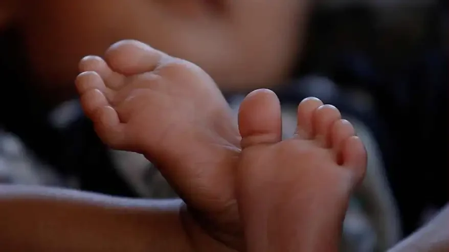 Primer plano de los pies descalzos de un bebé dormido, cruzados uno sobre otro.